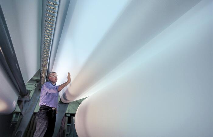 A man inspecting a giant roll of white paper